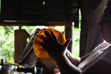 colombian peasant woman, making a yellow arepa with her hands. typical way of preparing breakfast...