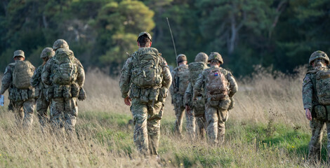 8 male and female British army soldiers tabbing with 25Kg bergens across open countryside, Wiltshire UK