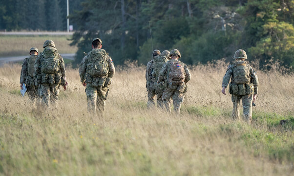 8 male and female British army soldiers tabbing with 25Kg bergens across open countryside, Wiltshire UK