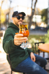Close-up of a glass of punch in a man's hands. A man holds a cocktail in his hands. Close-up of drink in man's hands.