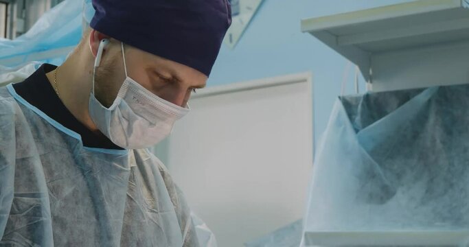 Close-up shot of an adult male professional surgeon with extensive experience. The face of the doctor is serious and focused on the process of work. Surgery concept.
