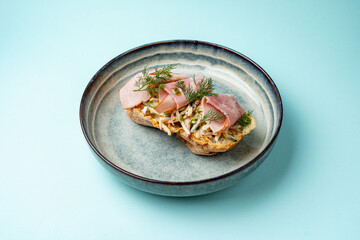 bruschetta with ham on a plate on a colored background