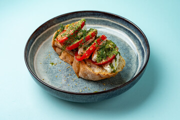 bruschetta with tomato mozzarella and pesto on a plate on a colored background