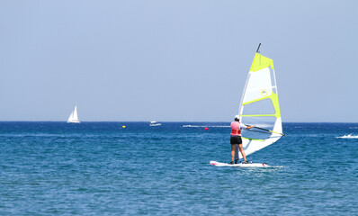 Riding on a board with a sail on the water.Active sea sports in summer.Sailing.