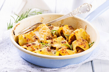 Traditional Italian paccheri pasta filled with minced meat and served with parmesan as close-up in a design pan