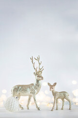 Silver reindeers on light background with christmas lights bokeh. Vertical stock image with copy space