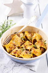 Traditional Italian canneroni pasta filled with minced meat and served with parmesan as close-up in...