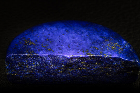 Polished deep blue Lapis lazuli rock macro isolated on black background. 
Dark blue Lapis lazuli with gold Pyrite spots.
Blue rock with gold details