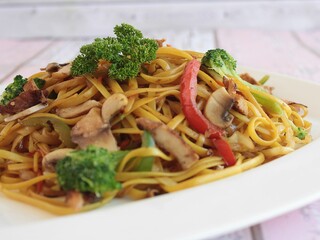 Selective focus of a plate of Teriyaki noodles with meat, mixed vegetables and mushroom sauce