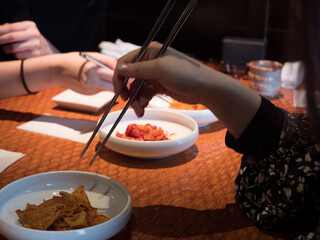 Hands picking at side dishes in a Korean restaurant - 540136401