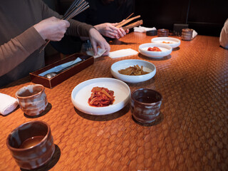 Hands picking at side dishes in a Korean restaurant - 540136472