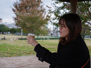 A beautiful Japanese lady drinking coffee in a park - 540136859