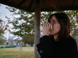 A beautiful Japanese lady drinking coffee in a park - 540137233