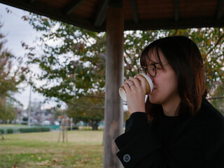 A beautiful Japanese lady drinking coffee in a park - 540137293