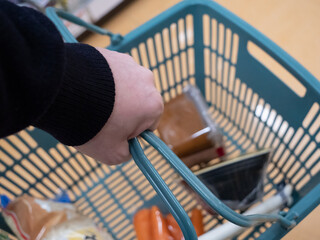 A young man's hand holding a shopping basket