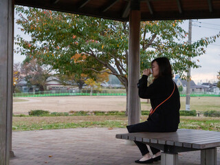 A young Asian lady sat a bench by herself - 540138260