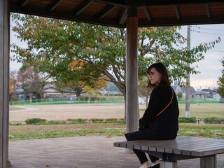 A young Asian lady sat a bench by herself - 540138462