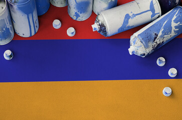 Armenia flag and few used aerosol spray cans for graffiti painting. Street art culture concept