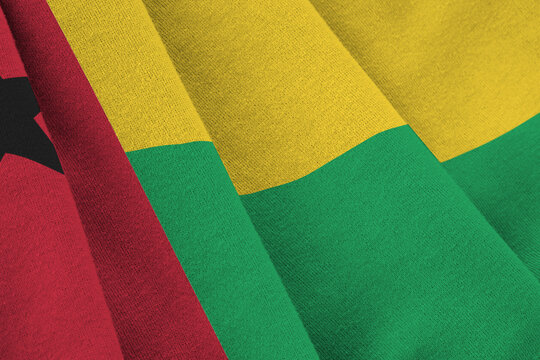 Guinea Bissau flag with big folds waving close up under the studio light indoors. The official symbols and colors in banner