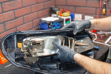 A master in black gloves installs a bi-diode lens in the headlight housing.Car headlight during...