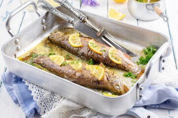 Traditional German fresh water char oven backed with lemon slice and olive oil served as close-up in a design alu casserole