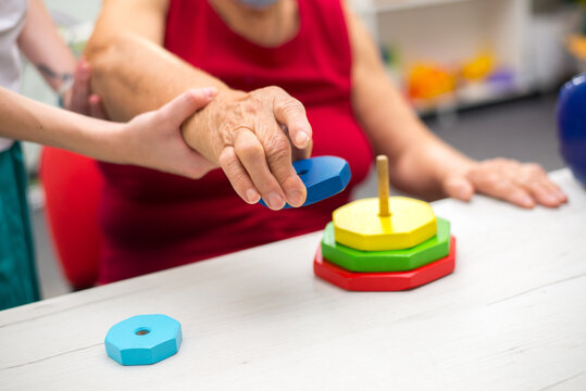 Old woman suffering from stroke exercising on physiotherapy with help of physiotherapist in the hospital