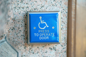 Blue handicapped access entrance pad for door mounted to a wall in Austin Texas