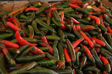 Heap of fresh Serrano peppers on counter at market, closeup