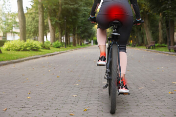 Problem of injured coccyx. Woman riding bicycle on road - obrazy, fototapety, plakaty