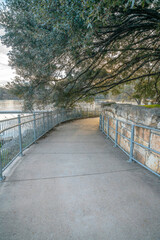 Paved pathway in Austin Texas along a river and under a canopy of trees