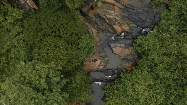 Drone flights straight down with camera pointing down into 3 people right on the side of a river in the middle of the jungle in Sri Lanka. Filmed close to Matughama