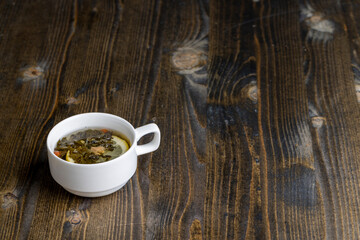 Green tea in a white cup during its brewing
