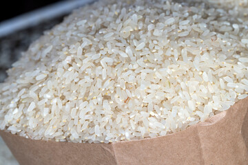 a pile of white rice in a paper bag and on the table