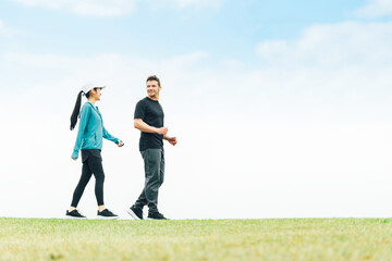 健康のため公園でウォーキング・散歩・有酸素運動するスポーツウェアを着た男女
