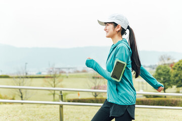 ダイエットのためウォーキング・運動中にスマホでフィットネスアプリを使うスポーツウェアのアジア人女性
