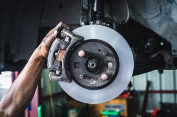 Auto mechanic checking car front brake rotors and brake pads. - obrazy, fototapety, plakaty