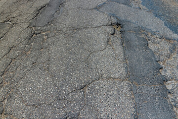An old paved road with a lot of holes and damage
