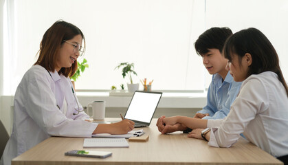 Smiling female gynecologist consulting couple for pregnancy planning at clinic. Family planning concept. © wattana