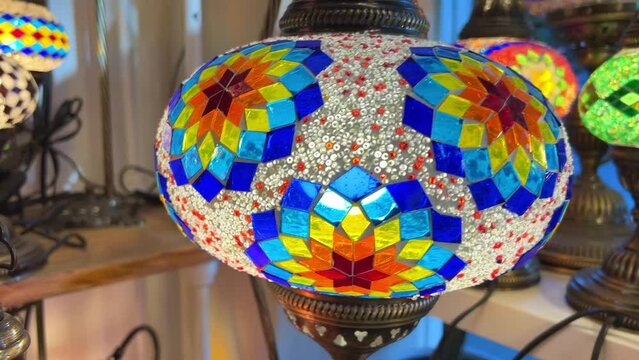 Bright multi-colored Turkish lamps hang in the store shine in different colors mosaic Colored stars and flowers painted on the lamps themselves
