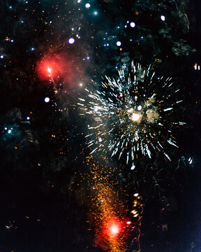 Colorful 4th Of July Fireworks In The Night Sky On July Fourth In The USA. Fireworks With A Smokey Red Background. Roman Candle Fireworks Celebration.