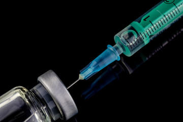 close up of glass medicine vial with syringe and needle isolated on black background. flu vaccine, doping in sport or  botox hualuronic collagen, drug addicted