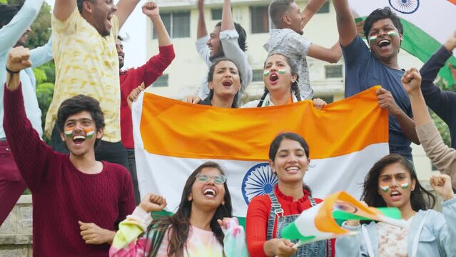 Group of audience at stadium shouting, screaming for win by holding indian flags while watching crcket sports match at stadium - concept of entertainment, championship tournament and entertainment