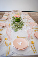 Mesa de fiesta con decorados rosas en cristalería y vajilla y flores en el centro