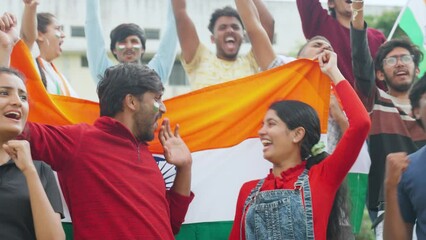 cheerful young couples with Indian flag shouting or screaming for win or for supporting team while watching cricket match at stadium - concept of excitement, championship and world cup match.