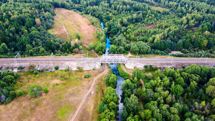 Fototapeta na wymiar railway bridge over a small river close-up view from above, bright colorful photo