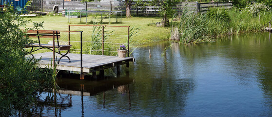 Handmade  pond and wooden pier in  poor Lithuanian  village