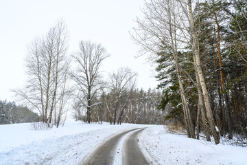 Obraz premium Snowy winter road in a mountain forest.