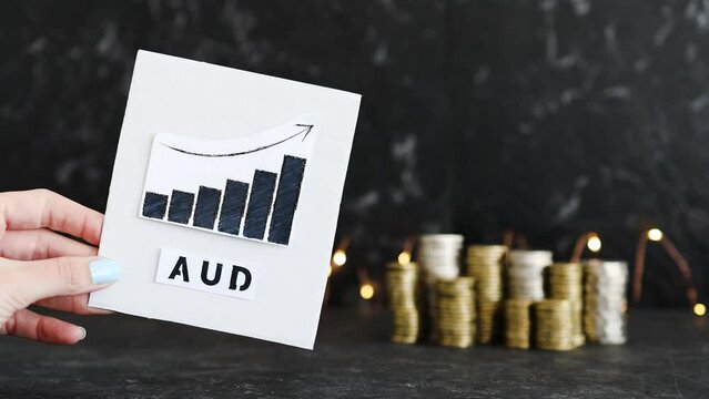 currency exchange rate, graph showing positive growth with AUD AUstralian Dollar text in front of stacks of coins