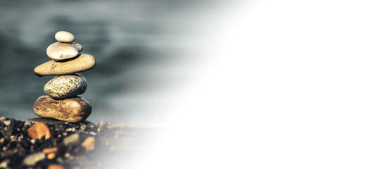 Pyramid stones balance on the sand of the beach. The object is in focus, and white background for your text. Relaxation.