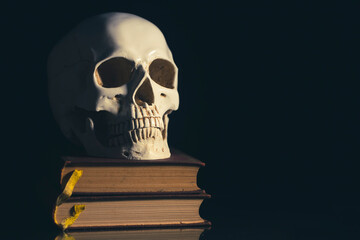 Human skull on vinatge books isolated on black background.